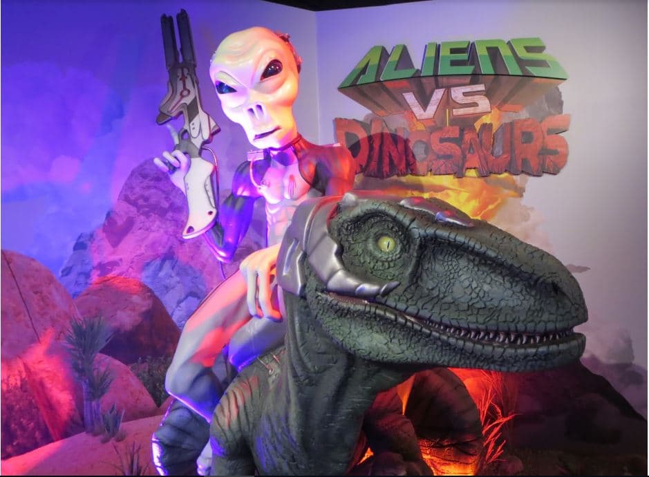a display of an alien statue riding on top of a velociraptor