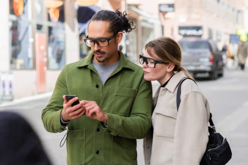 a man and woman look at a phone while wearing Tobii Pro Glasses 3